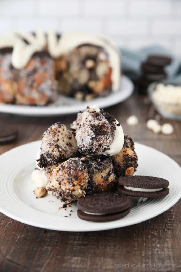 Front view of Oreo monkey bread pull apart on plate with cream cheese frosting and Oreo cookies.