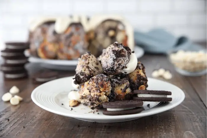 Front view of Oreo monkey bread pull apart on plate with cream cheese frosting and Oreo cookies.