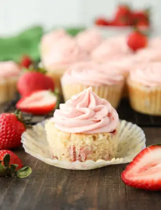 Strawberry cupcake in wrapper with strawberry buttercream on top.