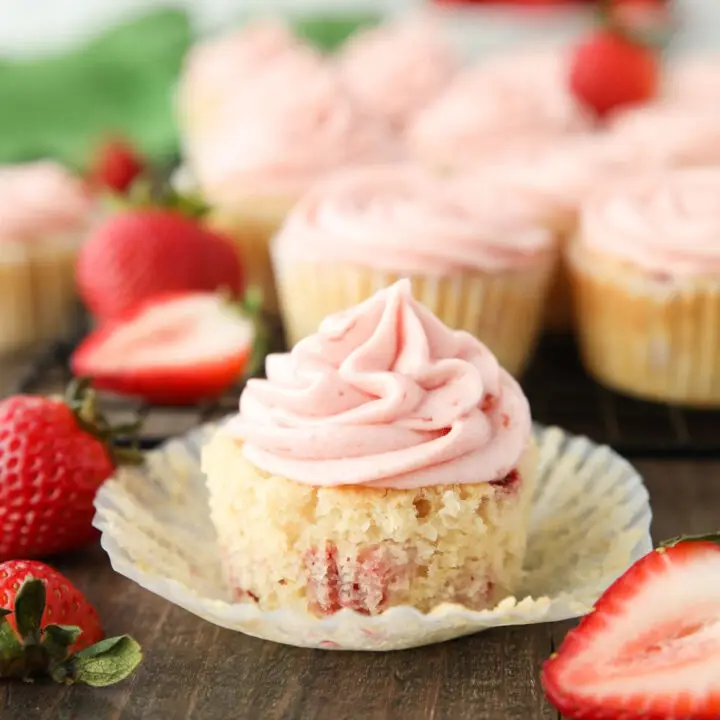 Strawberry cupcake in wrapper with strawberry buttercream on top.