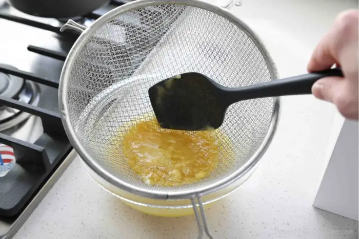 Straining lemon curd through a fine mesh strainer.