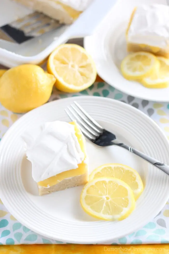 Lemon curd dessert square on plate made with a shortbread crust, sweetened cream cheese, lemon curd, and whipped cream.