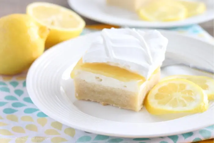 Lemon curd dessert square on plate made with a shortbread crust, sweetened cream cheese, lemon curd, and whipped cream.