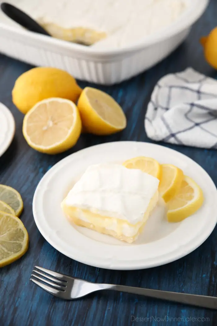 Lemon curd dessert square on plate made with a shortbread crust, sweetened cream cheese, lemon curd, and whipped cream.