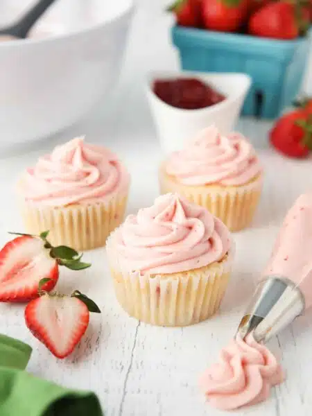Strawberry frosting piped onto cupcakes.