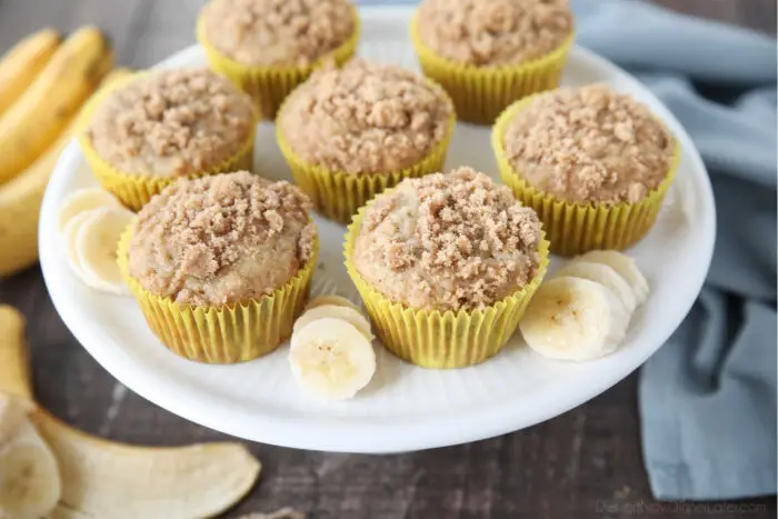 Top view of banana crumb muffins and banana slices on a cake plate.