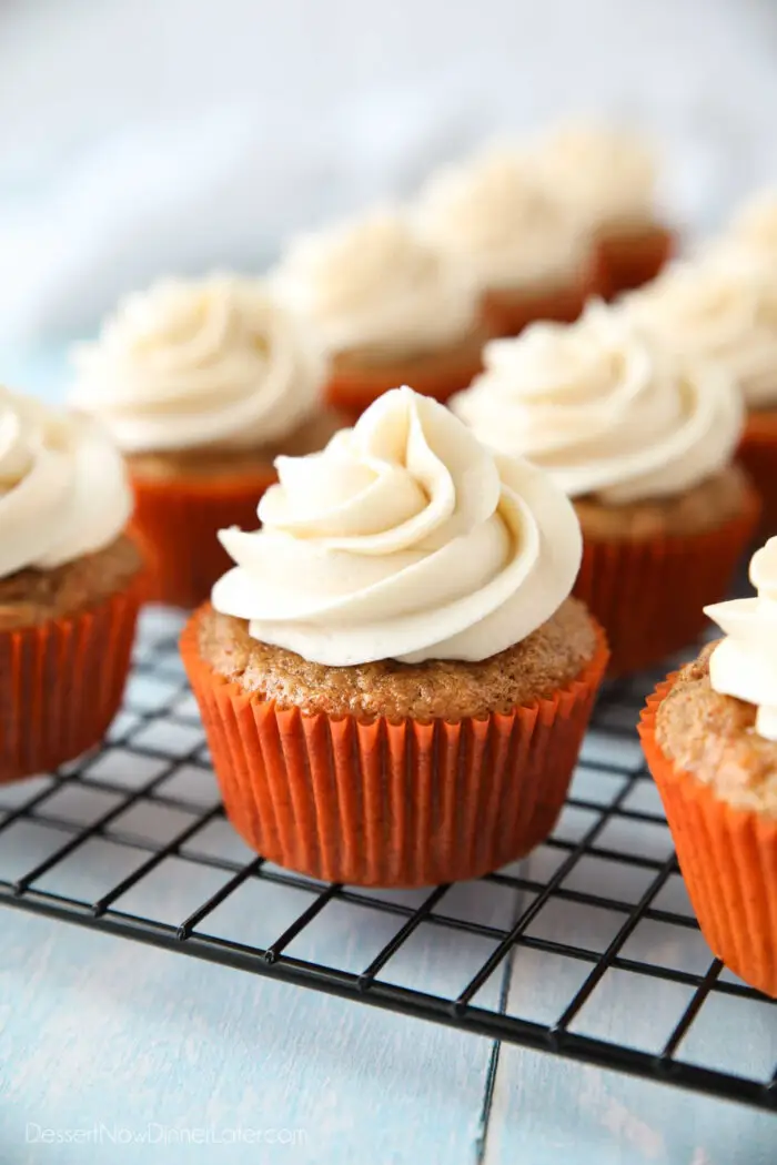 Cooling rack with cream cheese frosted carrot cake cupcakes.