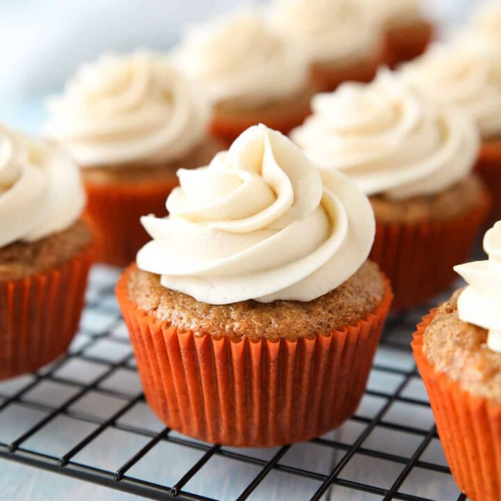 Cooling rack with cream cheese frosted carrot cake cupcakes.