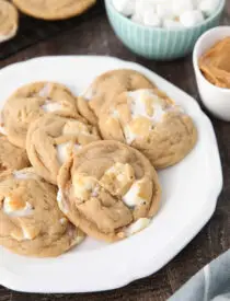 Fluffernutter cookies on a plate with bowls of mini marshmallows and peanut butter in the background.