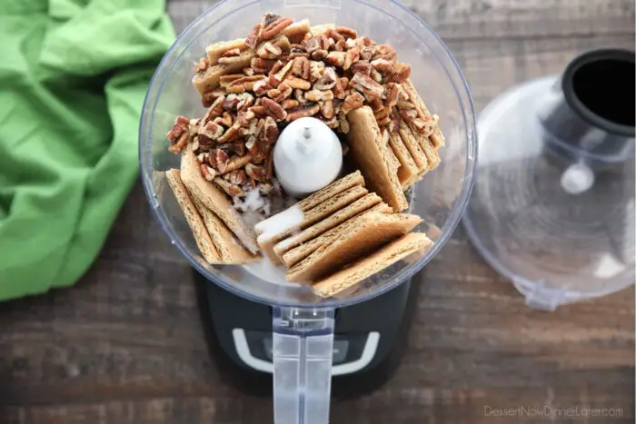 Food processor with graham cracker squares, pecan pieces, and granulated sugar for the crust.