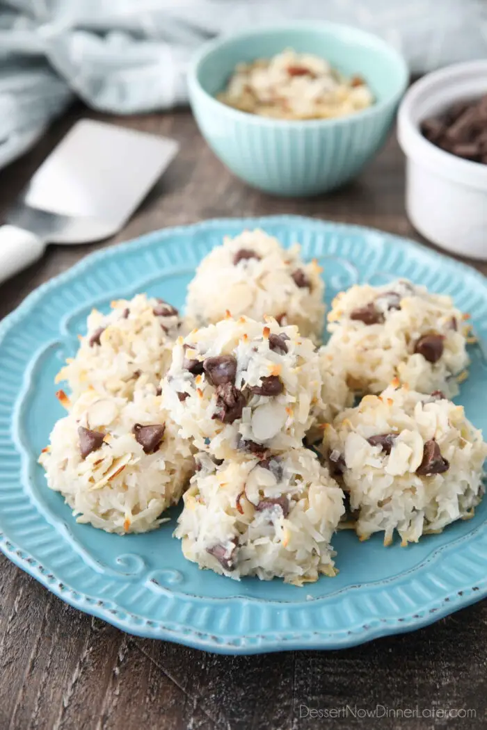 Angled view of plate of Almond Joy Macaroons with bowls of sliced almonds and chocolate chips in the background.