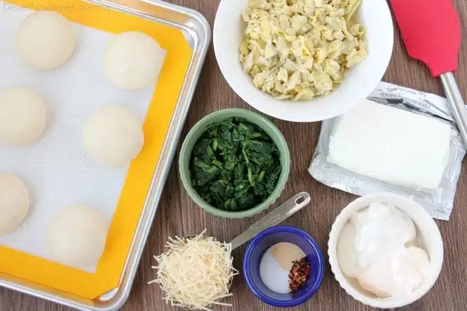 Ingredients for spinach artichoke cups: Rhodes rolls, frozen spinach, artichoke hearts, cream cheese, shredded parmesan cheese, mayonnaise, sour cream, salt, garlic powder, red pepper flakes.