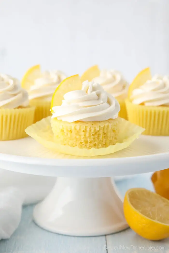 Side view close-up shot of lemon cupcake with wrapper peeled down to show fluffy texture.