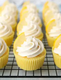 Cream cheese frosting with a lemon wedge on top of lemon cupcakes.