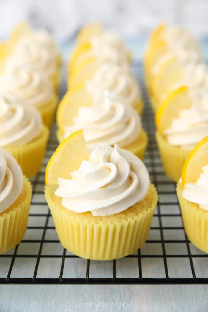 Cream cheese frosting with a lemon wedge on top of lemon cupcakes.