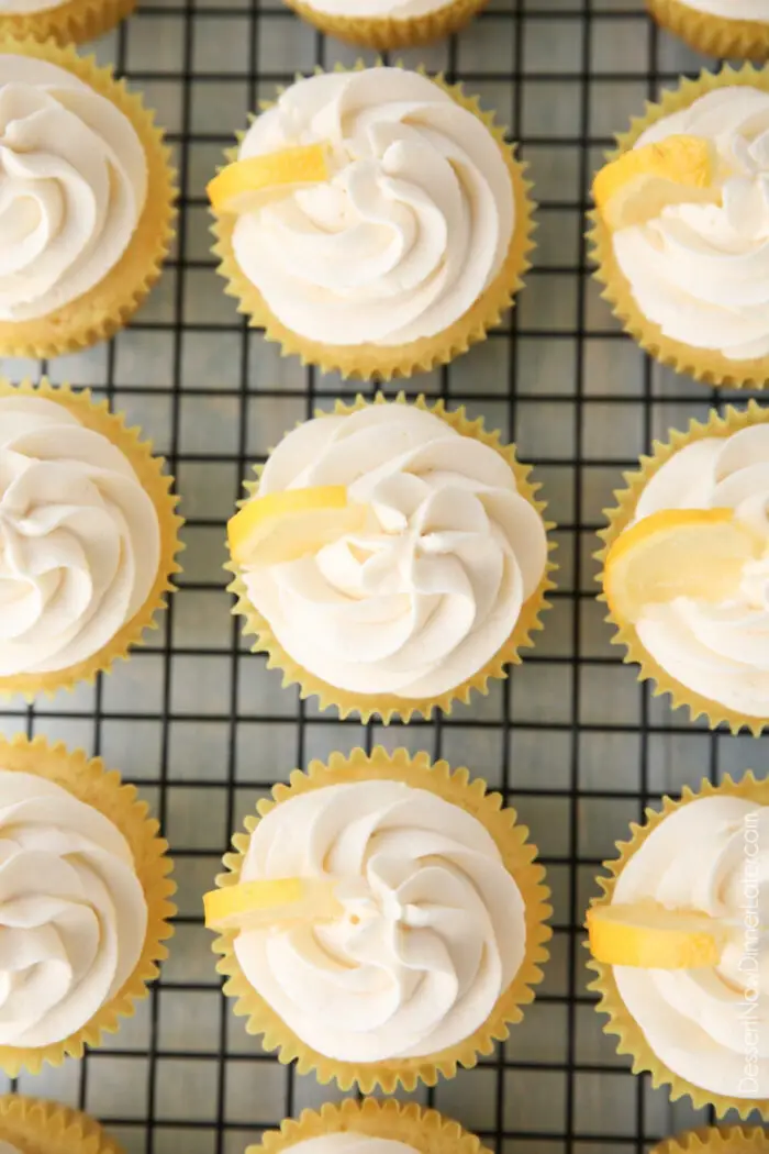 Top view of cream cheese frosting and lemon wedges atop lemon cupcakes.