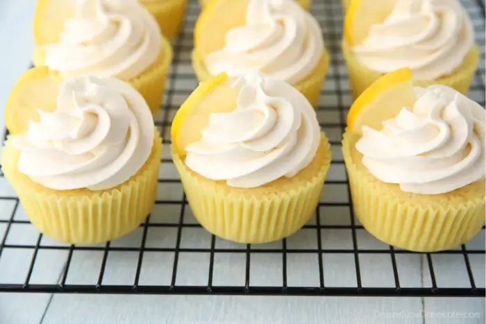 Cooling rack full of frosted lemon cupcakes.