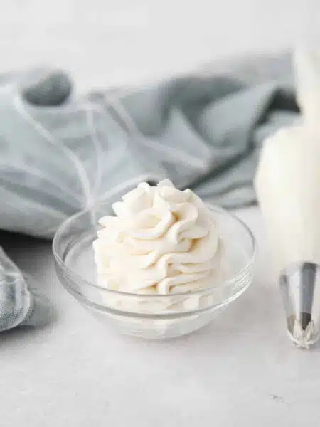 Whipped Cream Cheese Frosting piped high into a clear glass bowl.