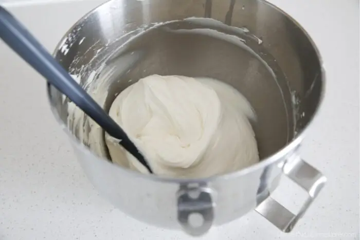 Whipped cream cheese frosting in mixing bowl with spatula.