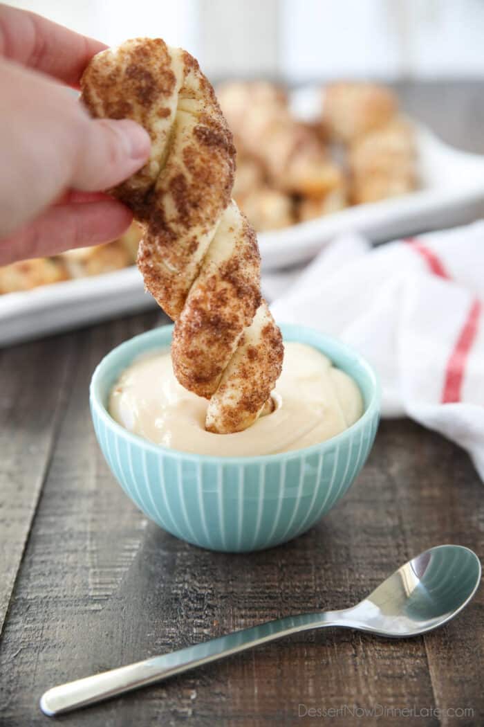 Dipping a cinnamon breadstick into a bowl of cream cheese glaze.