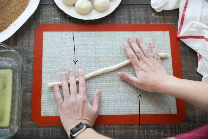 Demonstrating how to roll cinnamon twists. Rhodes dough is rolled into a long rope. Then each end is rolled in opposite directions.