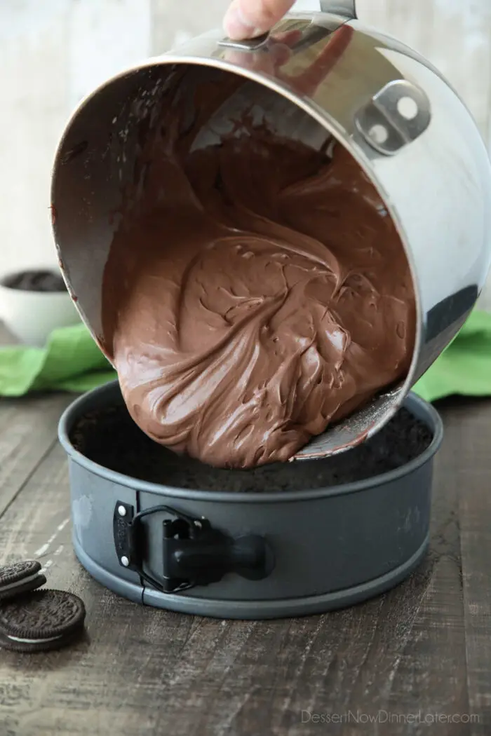 Chocolate cheesecake filling being poured into Oreo crust.