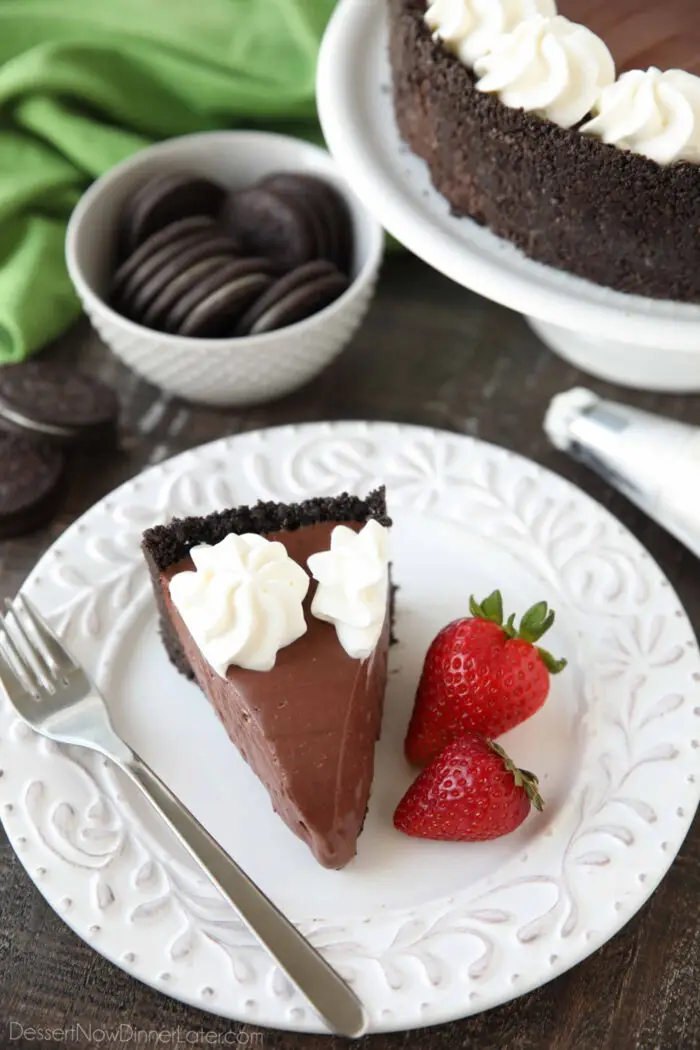 A slice of no bake chocolate cheesecake on a plate with fresh strawberries on the side.