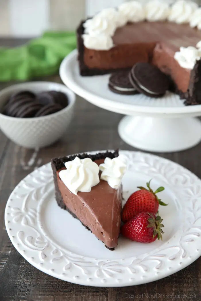 Slice of no bake cheesecake with whipped cream piped on top and strawberries on the side.