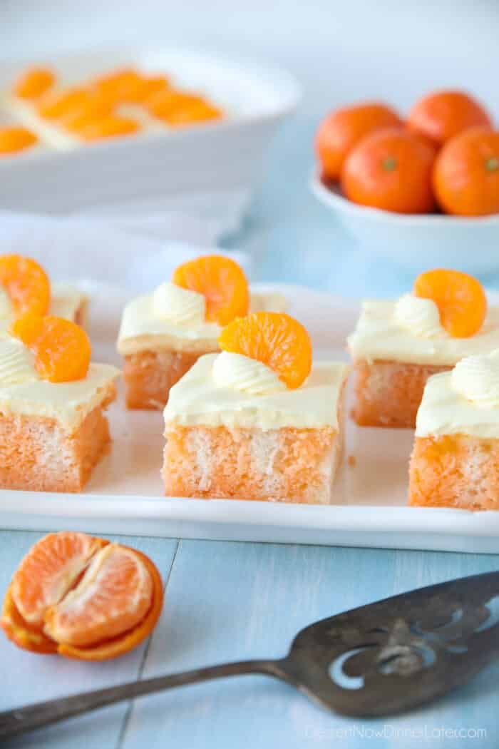 Slices of Orange Creamsicle Cake on a plate with mandarin orange slices on top.