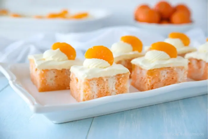 Marbled orange cake on plate with vanilla frosting and a mandarin orange slice on each piece.