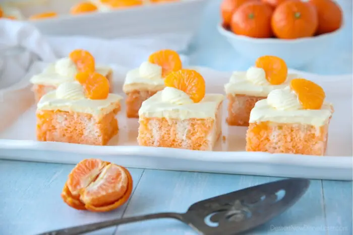 Slices of Orange Creamsicle Cake on a plate with mandarin oranges.