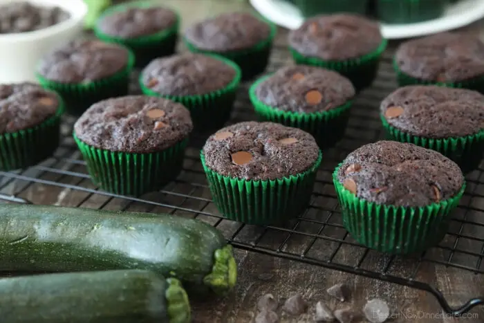 Side view of cooling rack with chocolate zucchini muffins in green paper wrappers.