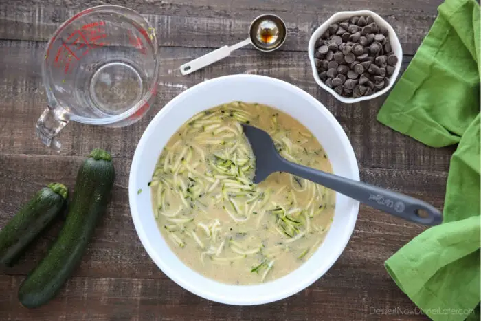 Wet ingredients mixed together in a bowl with the shredded zucchini.