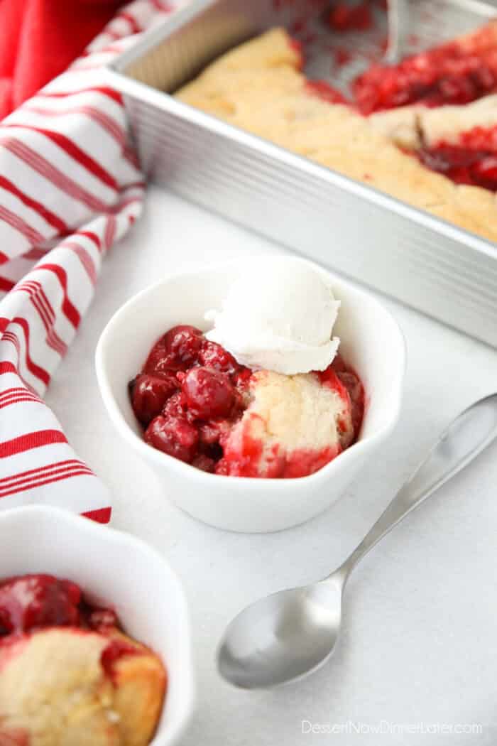 Cherry Cobbler in a bowl topped with vanilla ice cream and a spoon on the side.