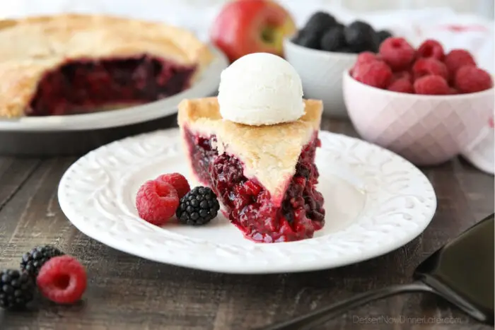 Slice of Razzleberry Pie on a plate topped with ice cream. Focus is on the berry pie filling.