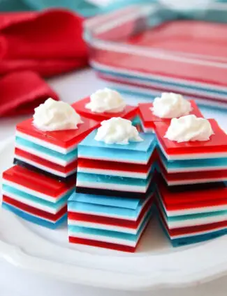 Red white and blue layered jello jigglers with whipped cream on top.