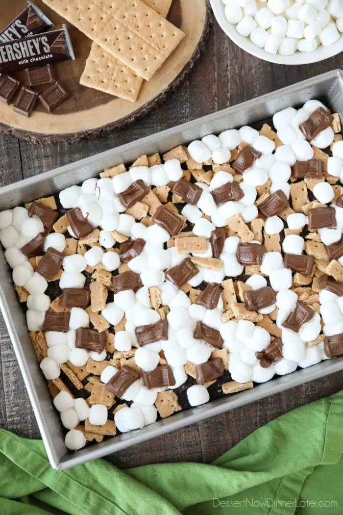 Top view of melted marshmallows and chocolate bars with graham cracker pieces on top of baked brownies.