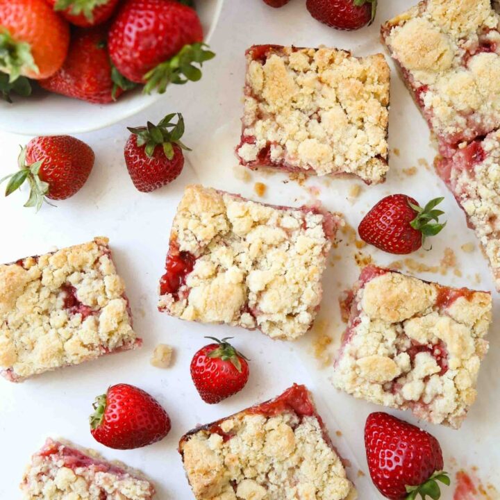Strawberry Crumb Bars cut into squares with fresh strawberries.
