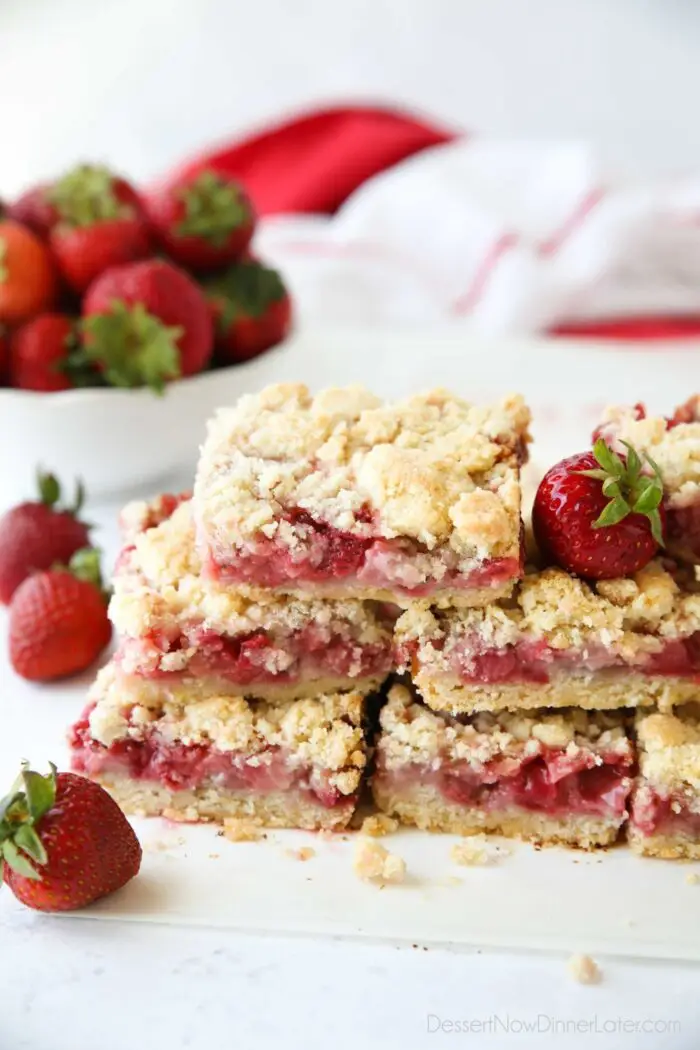 Stack of strawberry crumb bars with fresh strawberries.