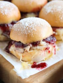 Close up of ham, turkey, and Swiss cheese mini sandwiches with raspberry preserves.