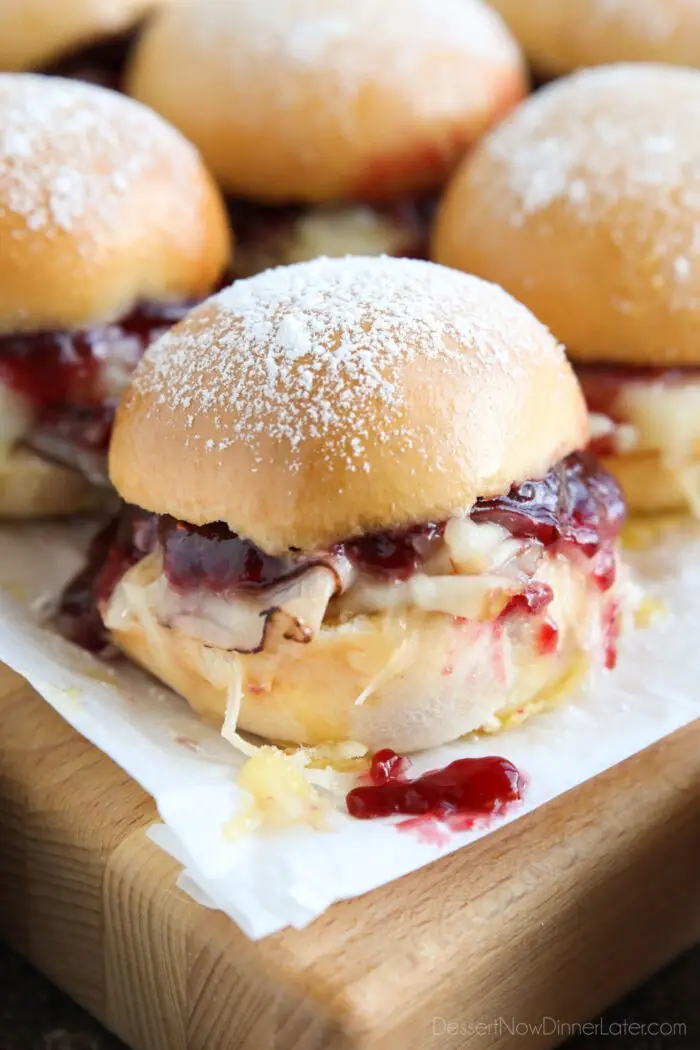 Close up of ham, turkey, and Swiss cheese mini sandwiches with raspberry preserves.