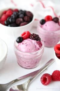 Scoop of berry frozen yogurt in a small glass mason jar with fresh berries on top.