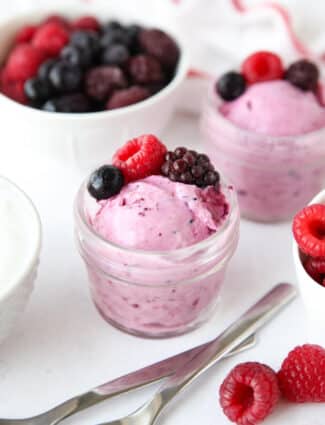 Scoop of berry frozen yogurt in a small glass mason jar with fresh berries on top.