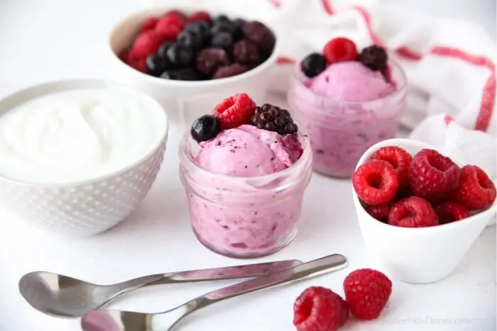 Berry frozen yogurt served inside of small mason jars with fresh berries.