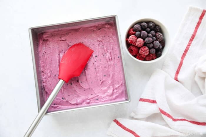 Berry frozen yogurt being spread into a shallow pan to freeze.