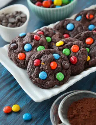 Chocolate cookies on a plate made with cocoa powder, chocolate chips and M&M's.