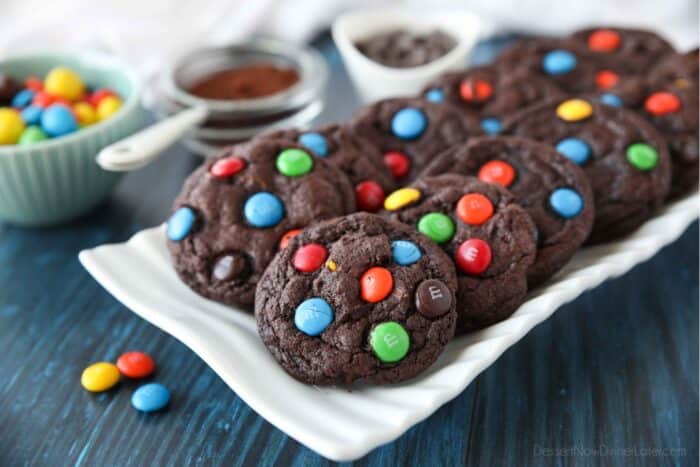 Serving platter of chocolate cookies with M&M's and chocolate chips inside.