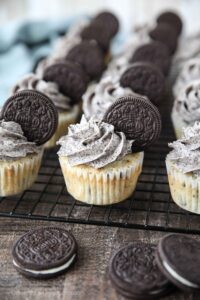 Closeup of vanilla cupcakes with Oreos inside and Oreo frosting on top with an Oreo cookie garnish.