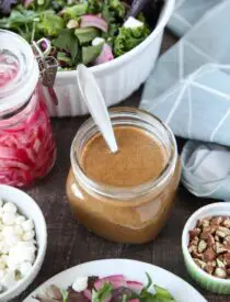 Focus on a glass mason jar of thick and creamy balsamic dressing with a spoon inside.