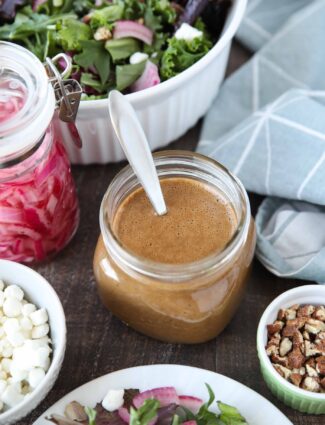 Focus on a glass mason jar of thick and creamy balsamic dressing with a spoon inside.
